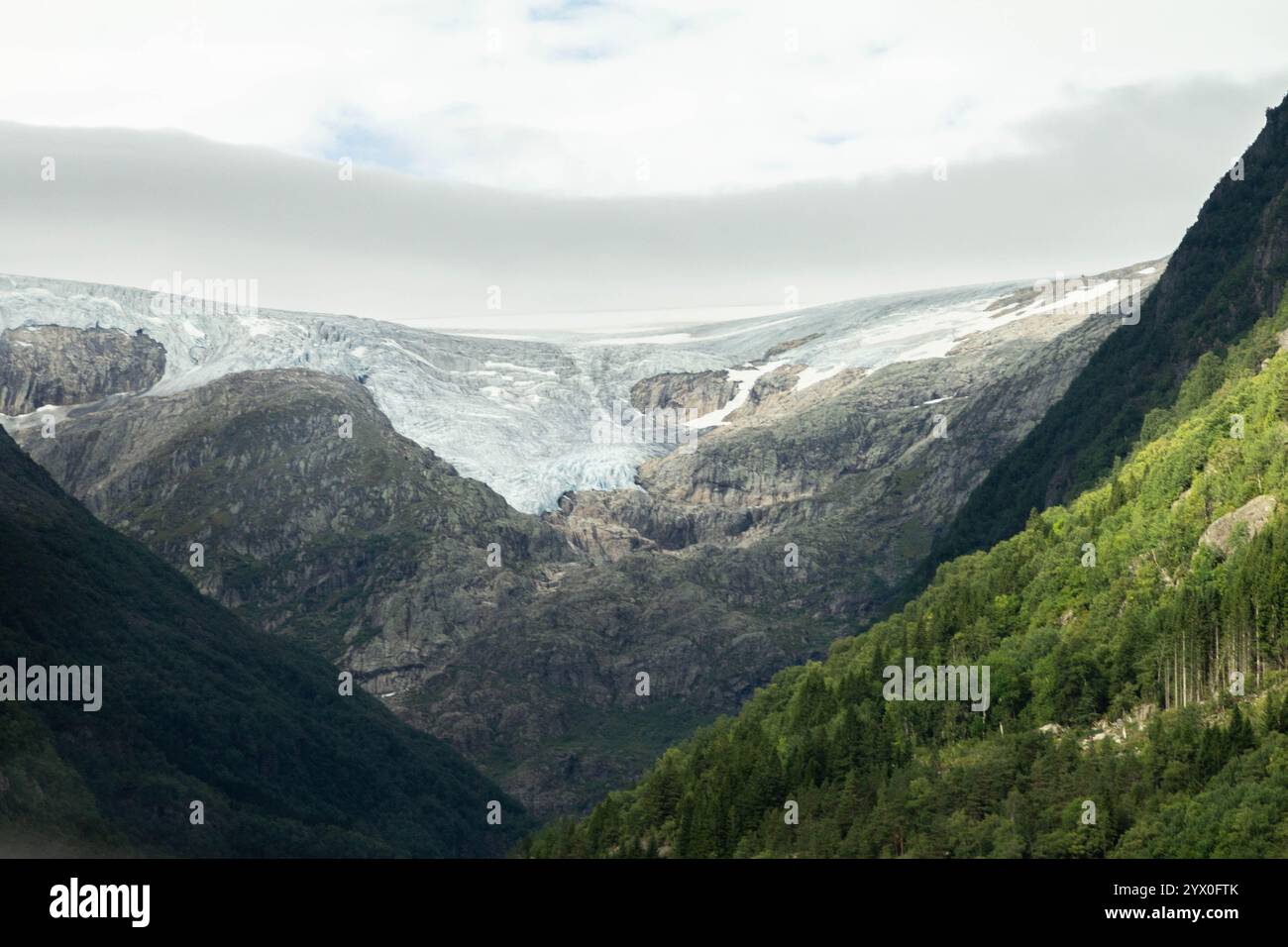 Uno splendido ghiacciaio si estende attraverso l'aspra montagna, la sua superficie ghiacciata che contrasta con il terreno roccioso circostante. La vasta distesa di neve Foto Stock