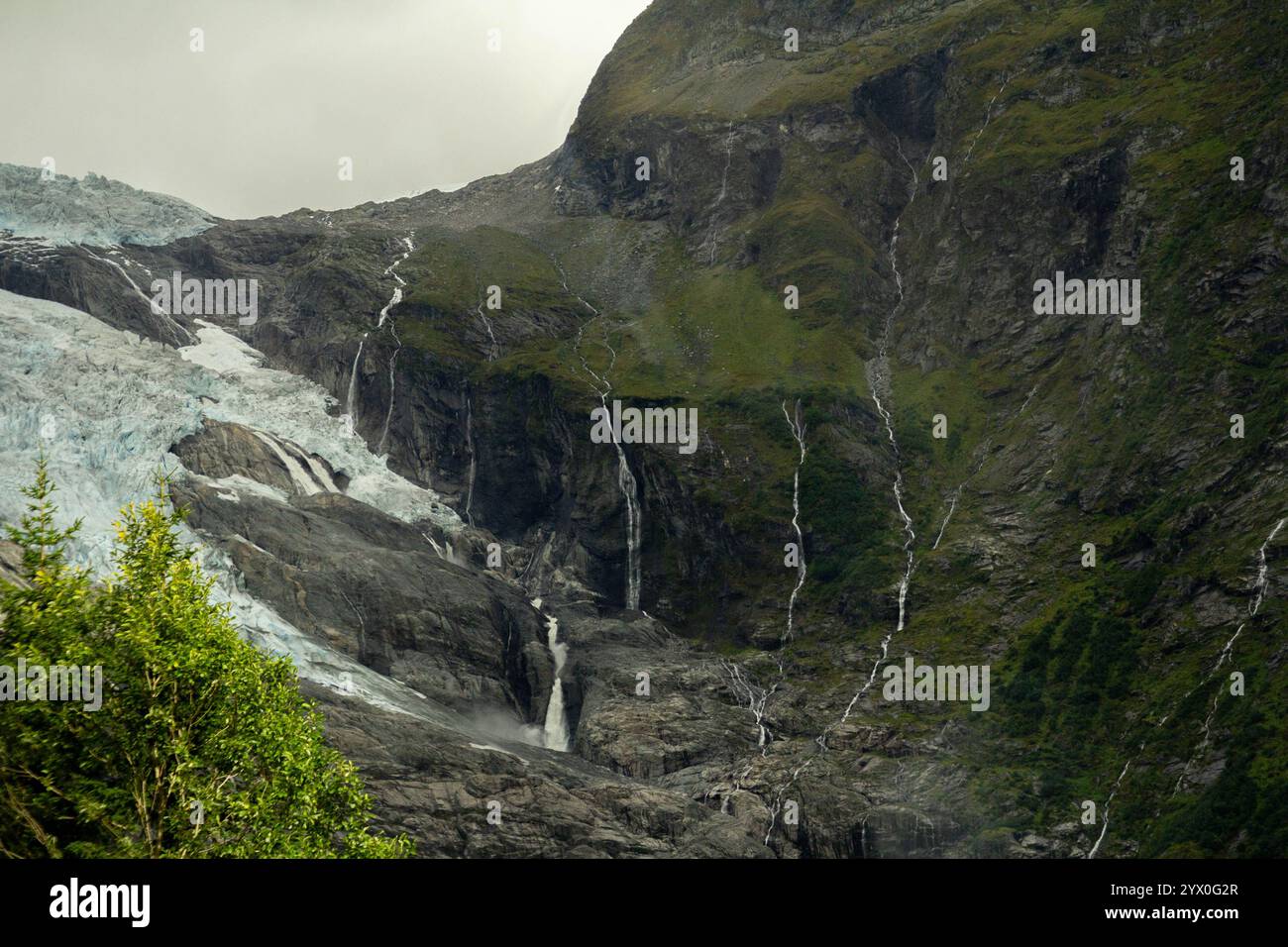 Uno splendido ghiacciaio si estende attraverso l'aspra montagna, la sua superficie ghiacciata che contrasta con il terreno roccioso circostante. La vasta distesa di neve e.. Foto Stock