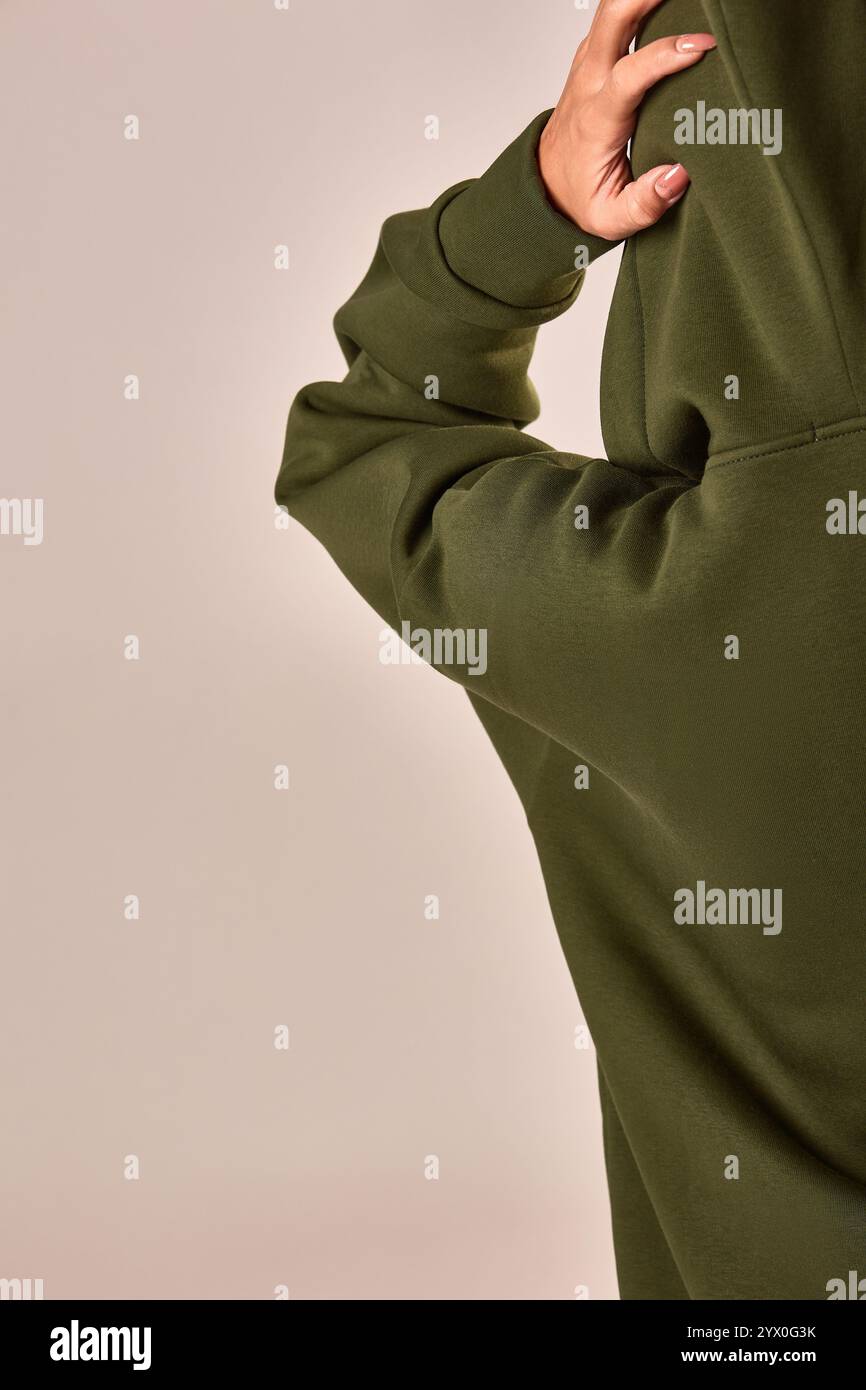 Vista ravvicinata di una mano sul retro che indossa una felpa verde che enfatizza il concetto di stile casual e comfort Foto Stock