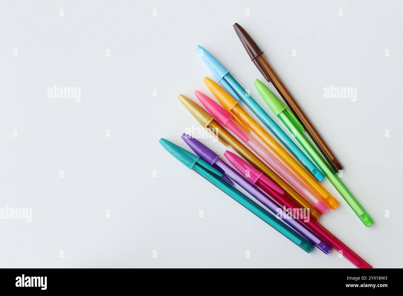 Un mucchio di penne colorate disposte in diagonale su sfondo bianco. Cancelleria a colori, forniture scolastiche, lezione d'arte, concetto di creatività. Foto Stock