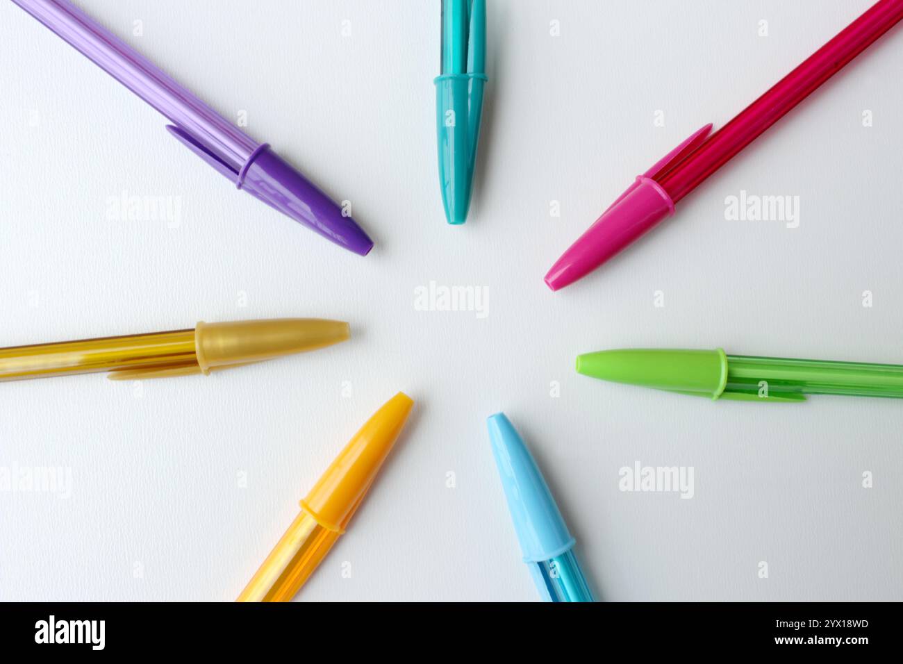 Penne colorate disposte in cerchio su sfondo bianco. Materiale scolastico di cancelleria dai colori brillanti. Creatività, arte, immaginazione. Foto Stock