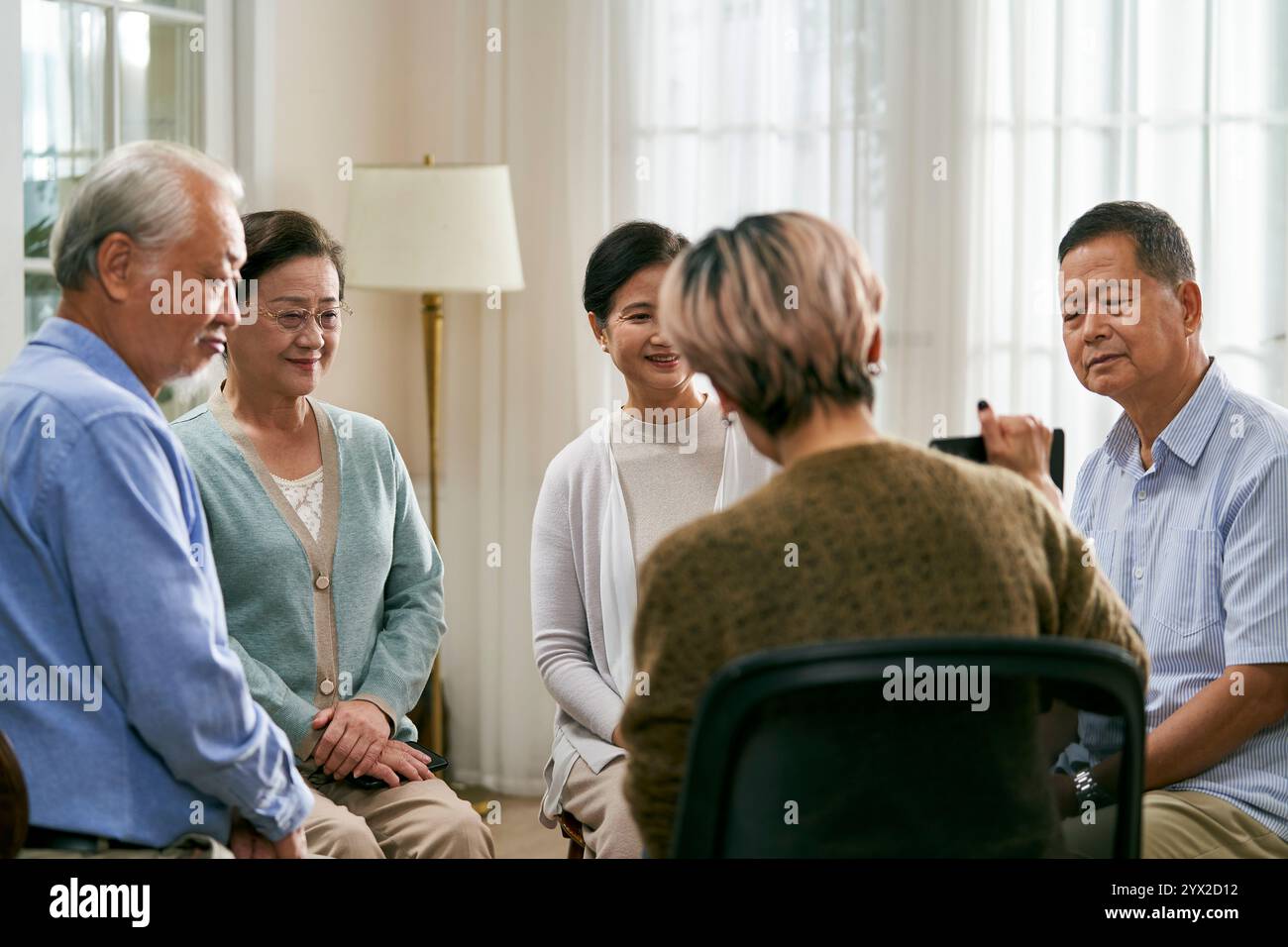 consulente donna asiatica che conduce una sessione di discussione per un gruppo di anziani Foto Stock