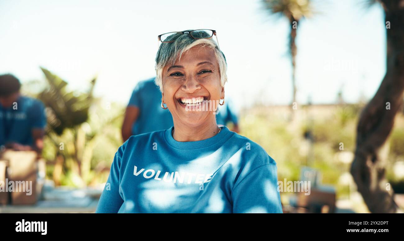 Beneficenza, ritratto e sorriso di una donna volontaria all'aperto nel parco per un'iniziativa alimentare comunitaria o una donazione. Attivismo, aiuto e società con felice maturità Foto Stock
