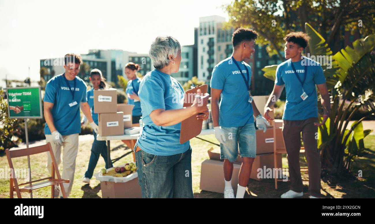 Beneficenza, appunti e lavoro di squadra con gruppo di volontari all'aperto nel parco per un'iniziativa alimentare comunitaria o una donazione. Attivismo, aiuto e società felici Foto Stock