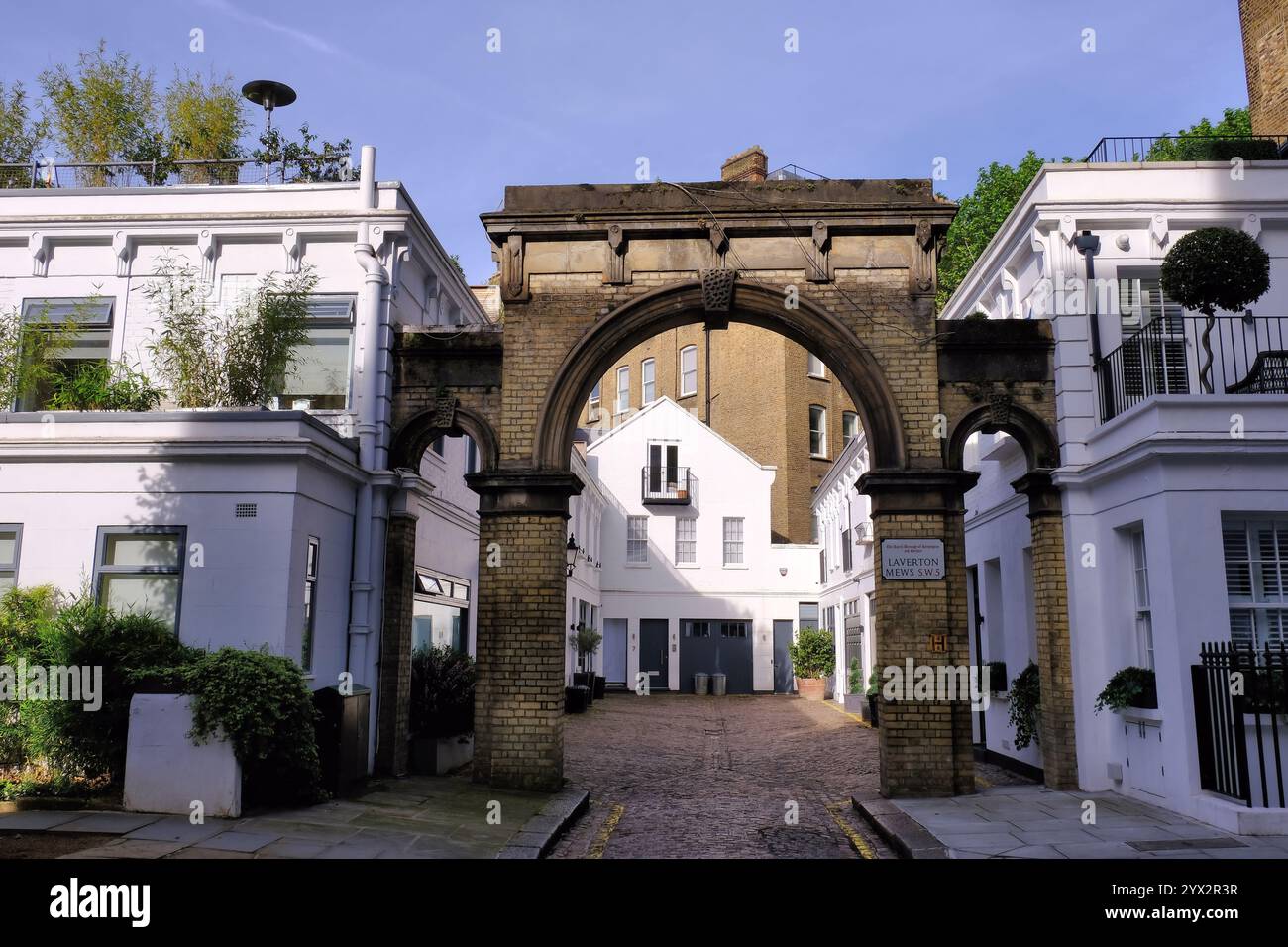 Vecchia arcata in mattoni, case con terrazza in stucco bianco e ciottoli a Laverton Mews, Earls Court, Londra, Inghilterra, Regno Unito Foto Stock