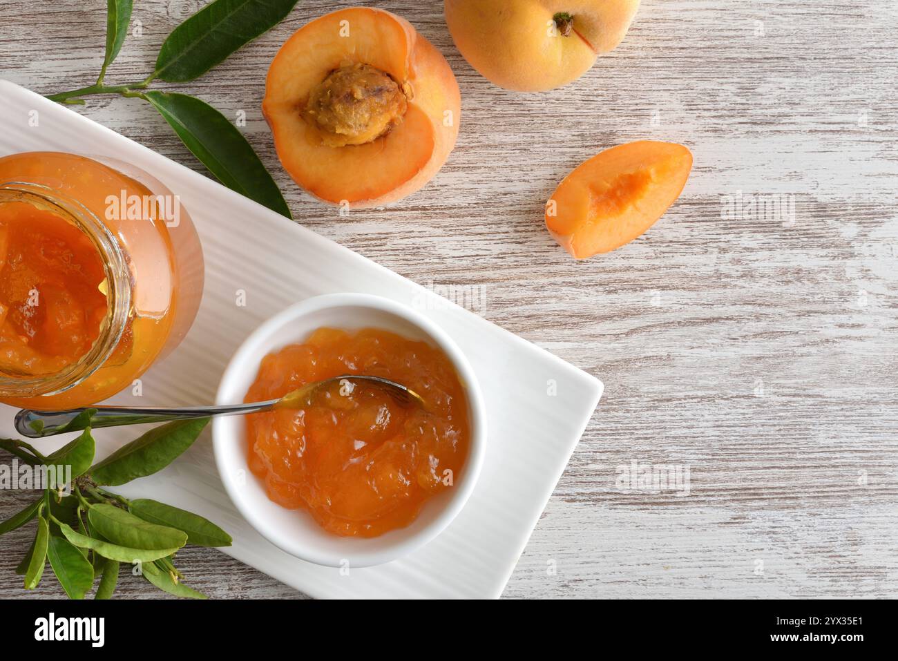 Marmellata di pesca e pezzi di frutta su un tavolo di legno con un piatto. Vista dall'alto. Foto Stock