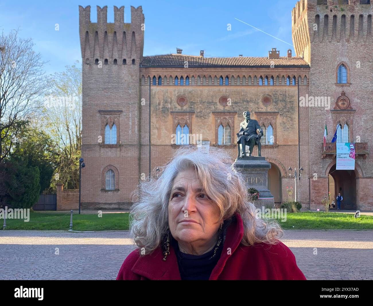 Busseto, Parma, Italia - 23 novembre 2024 Una donna si erge in piazza giuseppe verdi a busseto, italia, con la statua del compositore giuseppe verdi e la statua del padre Foto Stock