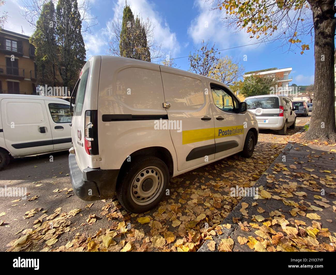 Lugagnano D'Arda PC, Italia - 27 novembre 2024 furgone bianco poste italiane parcheggiato in una strada residenziale ricoperta di foglie autunnali cadute Foto Stock
