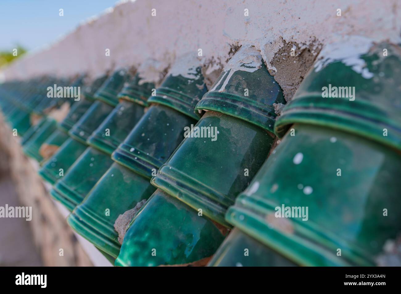 Vista della parte superiore della recinzione coperta da bellissime piastrelle verdi del tetto Foto Stock