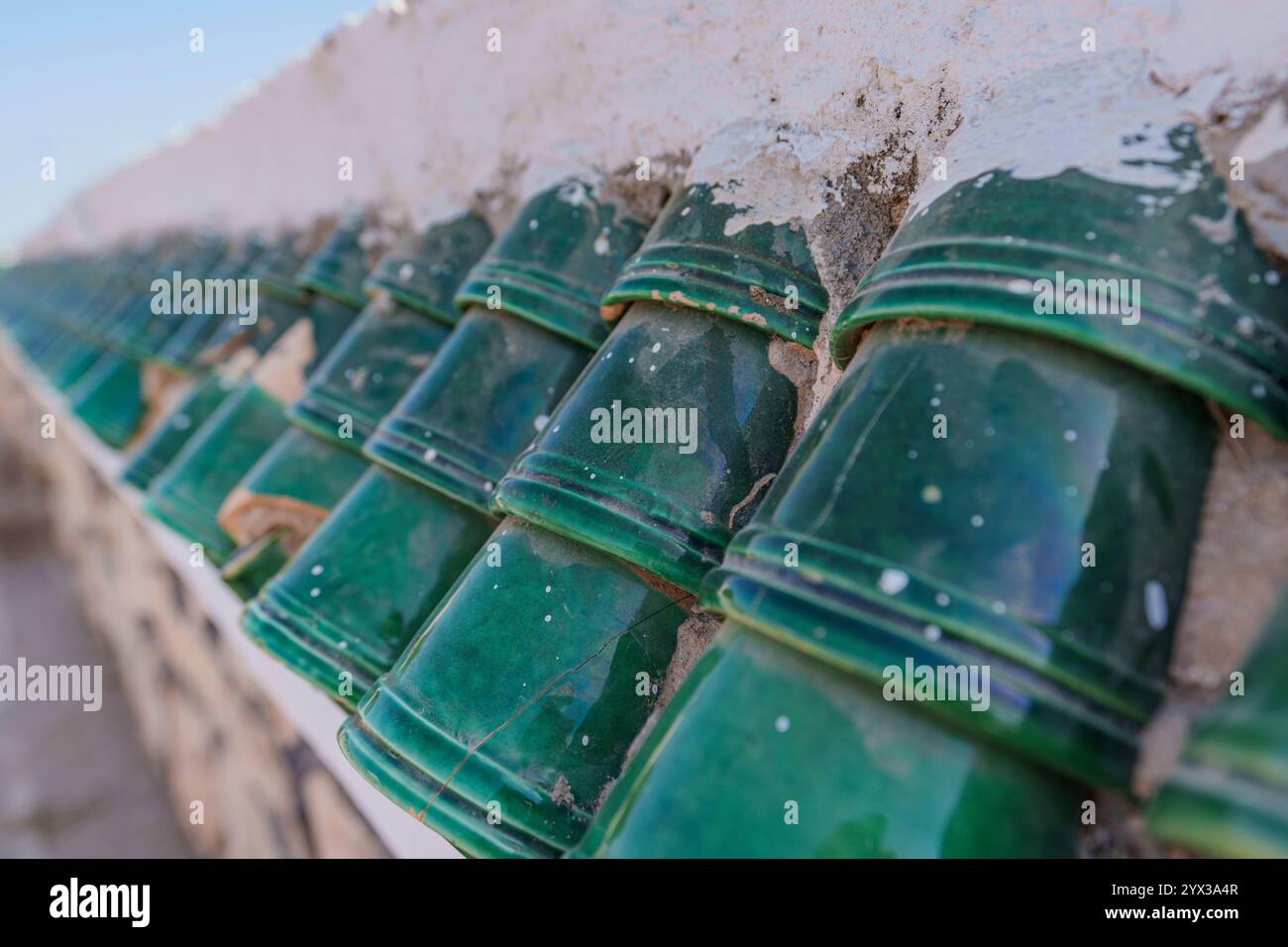 Vista della parte superiore della recinzione coperta da bellissime piastrelle verdi del tetto Foto Stock