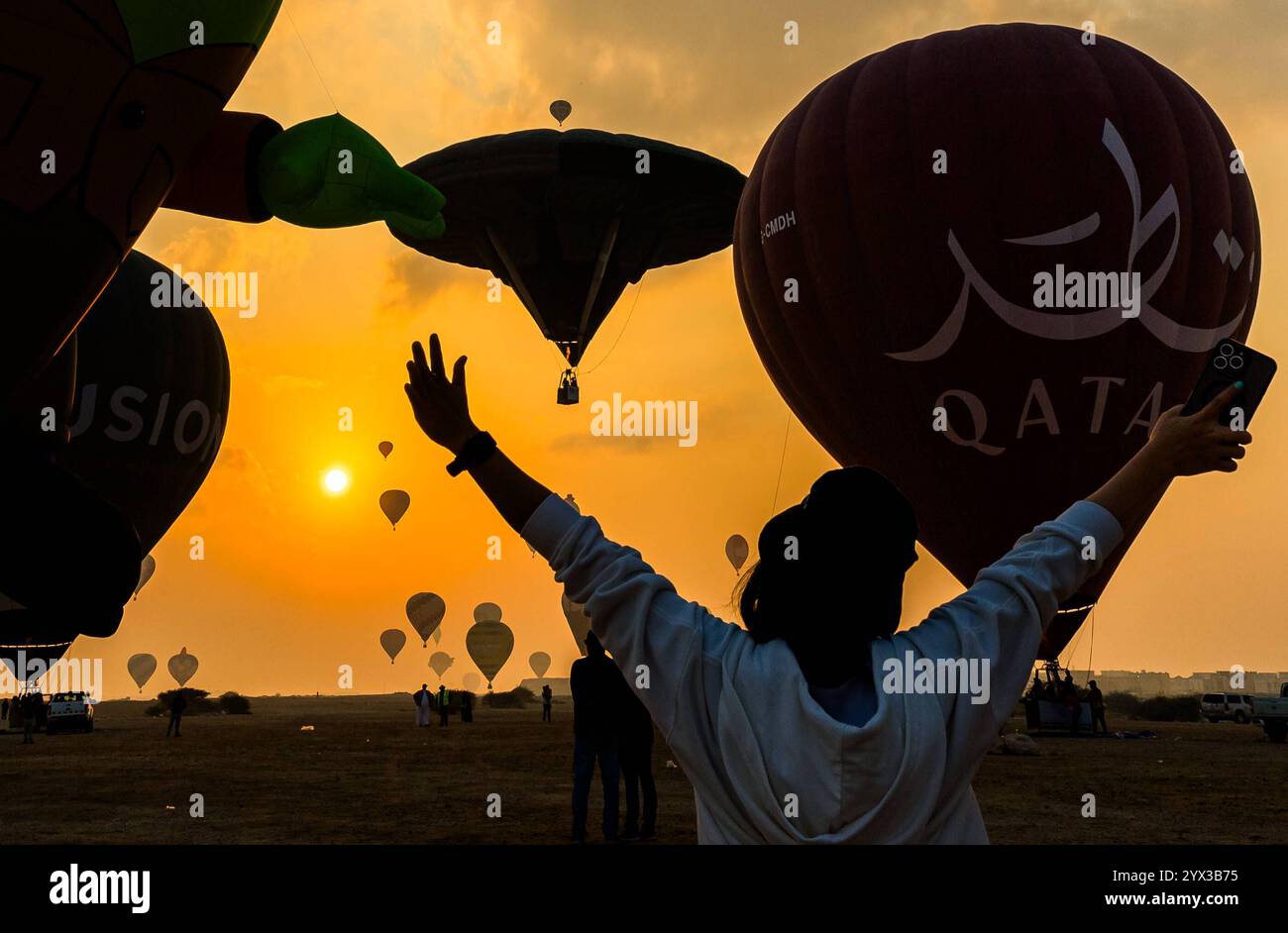 QATAR BALLOON FESTIVAL 2024 persone guardano le mongolfiere decollare all'alba durante il Qatar Balloon Festival 2024 a Doha, Qatar, il 13 dicembre 2024. La quinta edizione del Qatar Balloon Festival si è tenuta qui dal 12 al 22 dicembre e più di 50 partecipanti partecipano al Festival DOHA Qatar Copyright: XNOUSHADx Foto Stock