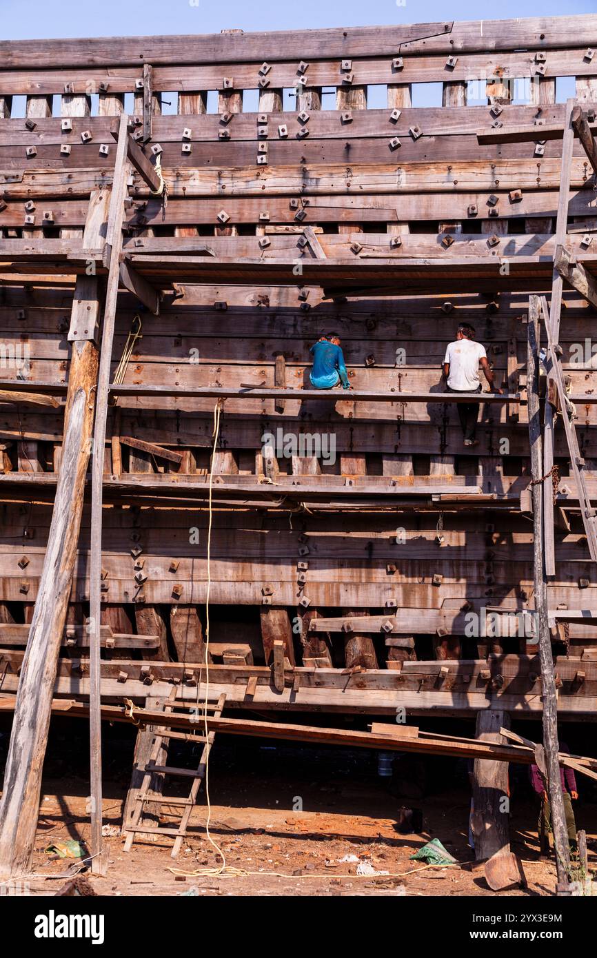 Costruttori navali che lavorano su una barca in legno in costruzione, Mandvi, Gujarat, India Foto Stock