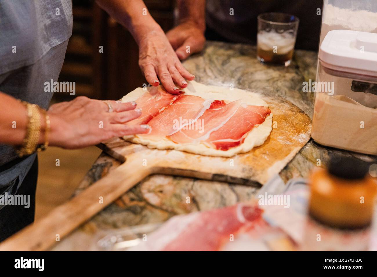 A strati di prosciutto sull'impasto della pizza per una pizza fatta in casa Foto Stock
