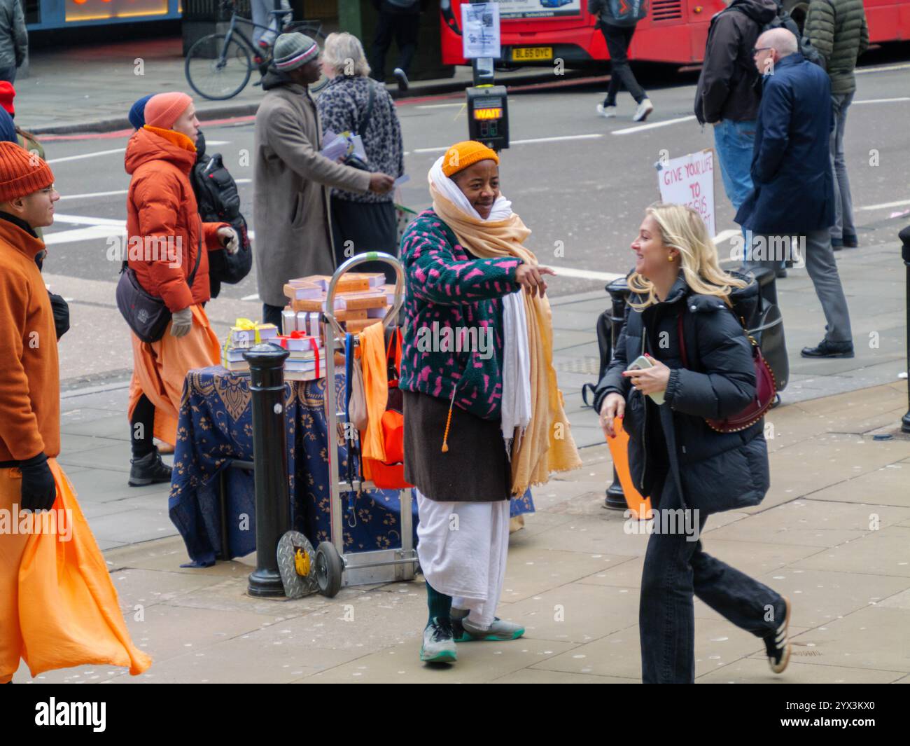 I devoti di Hare Krishna distribuiscono libri di meditazione Yoga ai pedoni a Bishopsgate, Londra, Regno Unito. Foto Stock