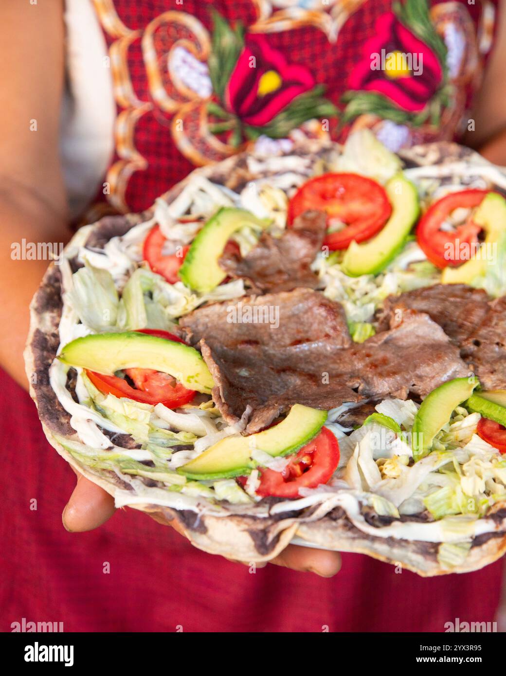 Il Tlayuda è una tortilla sottile e croccante con fagioli neri, carne di manzo, pomodoro e avocado. È un tradizionale cibo messicano di Oaxaca. Foto Stock