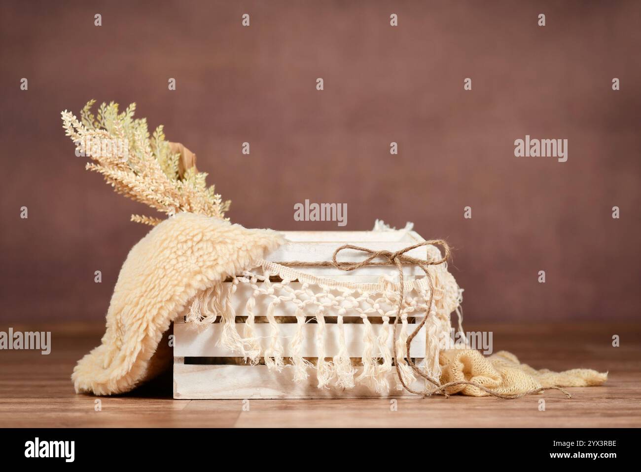 Sfondo digitale neonato con scatola di legno bianca vuota e ghirlanda di makramee su sfondo marrone Foto Stock