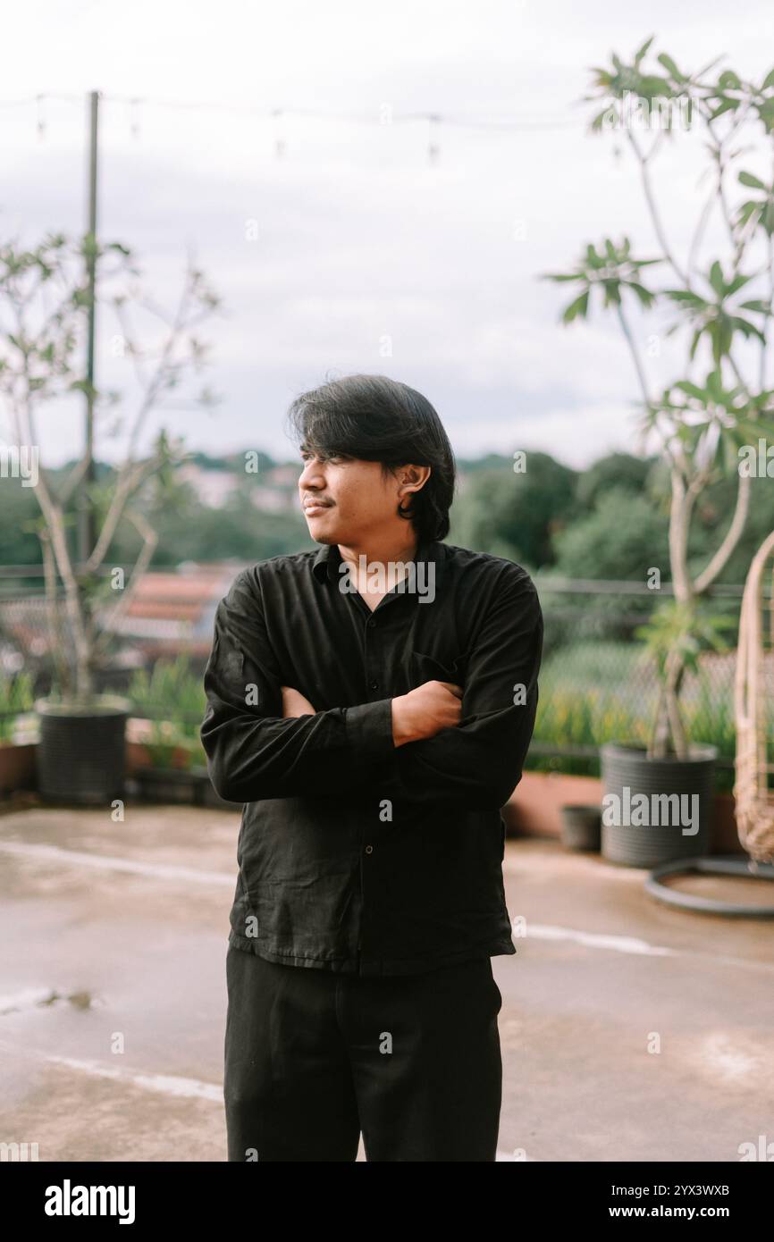 Un uomo del sud-est asiatico che attraversa le braccia, trasudando fiducia e contemplazione. Perfetto per progetti di stile di vita, ritratti o concettuali che presentano atti Foto Stock