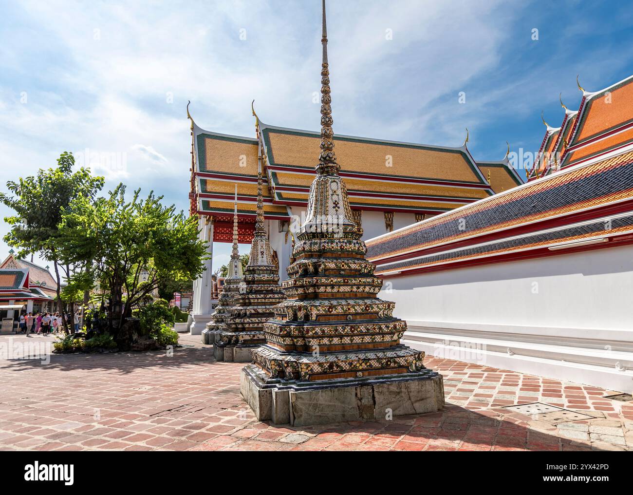 Chedi decorato in ceramica con una slanciata guglia accanto alle bianche mura del tempio e ai tetti a strati a Wat Pho, Bangkok, Thailandia Foto Stock