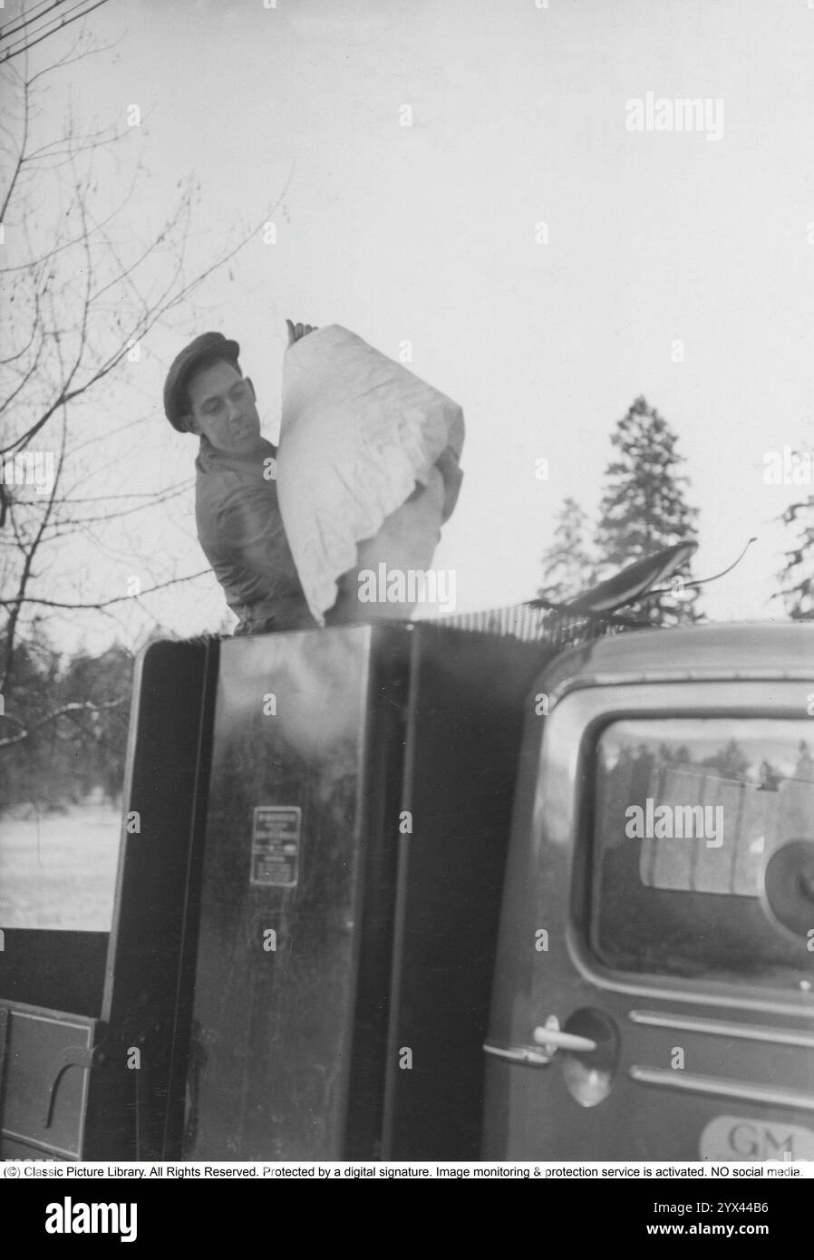 Gas di legno 1942. Un uomo riempie più carbone nel contenitore per alimentare l'unità gas di legno. Una caratteristica naturale durante questi anni durante la seconda guerra mondiale era l'unità di gassificazione Wood su auto e camion. Il gas di legno è un gas che deriva dalla combustione incompleta di legno o carbone ed è stato utilizzato per alimentare i veicoli. Il conducente doveva riempire il carbone da solo e assicurarsi che la combustione funzionasse come dovrebbe. A causa della mancanza di carburante durante la seconda guerra mondiale, il gas di legno giocò un ruolo importante nel mantenere i trasporti in funzione. Foto Stock