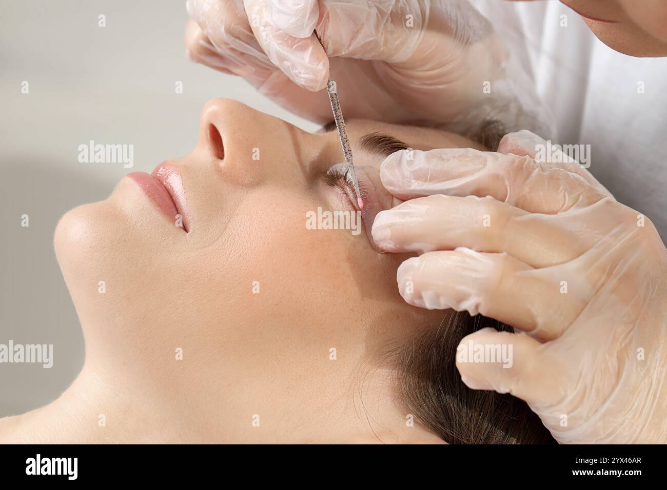 Procedura di laminazione delle ciglia. Estetista che attacca le ciglia della donna per immergerle nel salone di bellezza, primo piano Foto Stock