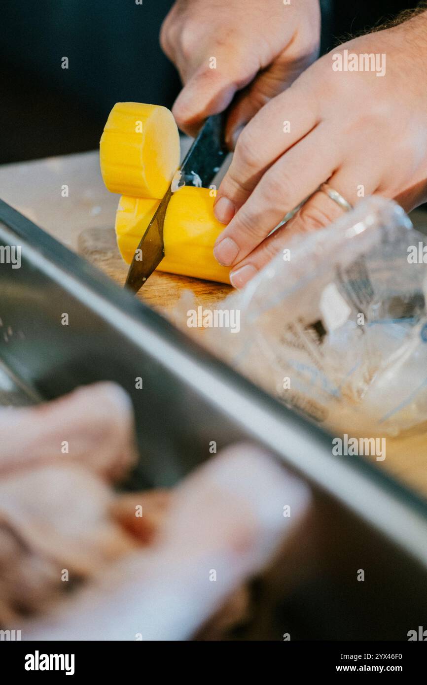 Una persona sta usando un coltello per tagliare un frutto giallo Foto Stock