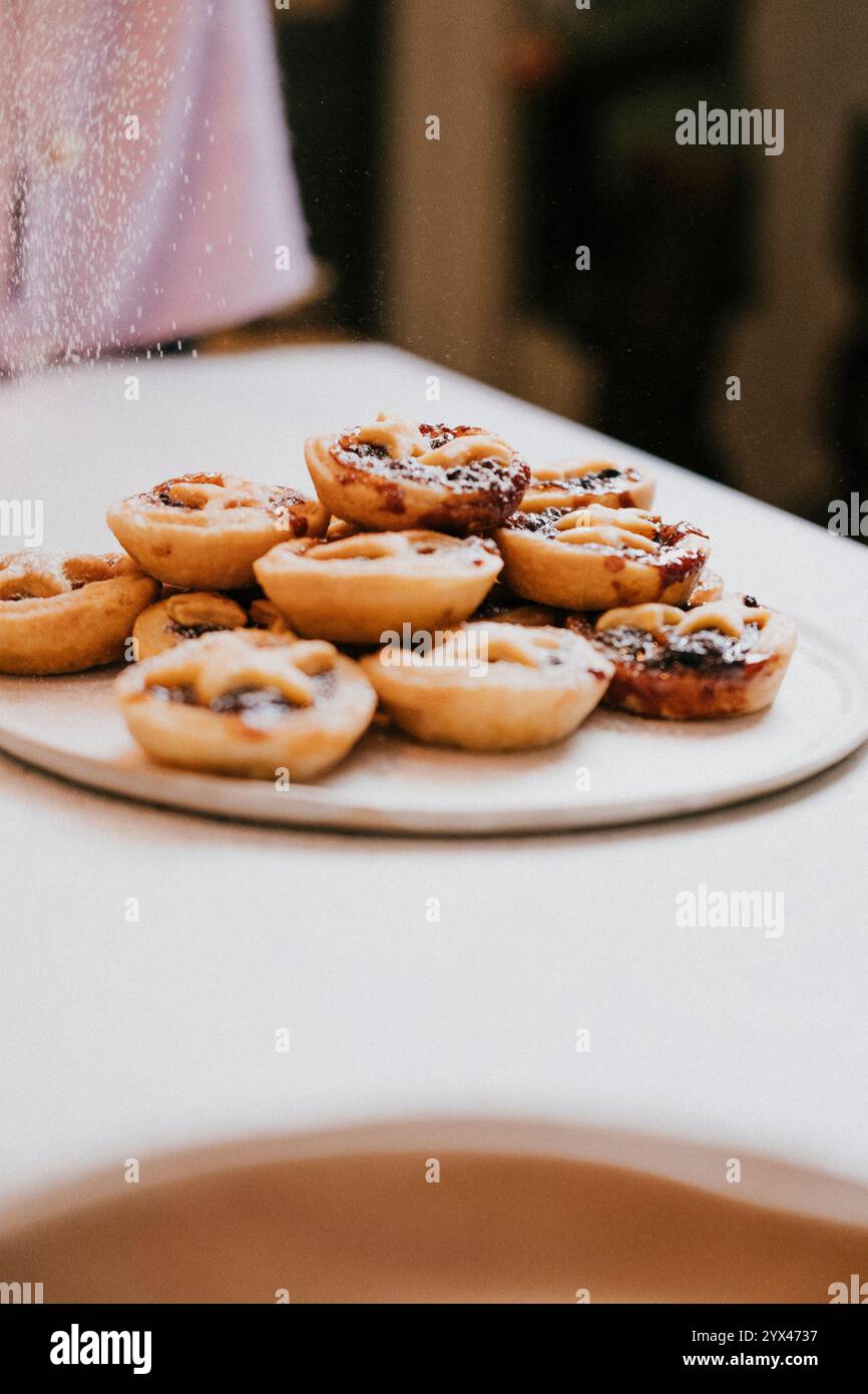 Un piatto di pasticcini con una persona sullo sfondo. I dolci sono impilati l'uno sull'altro e sembrano essere preparati al momento Foto Stock Un piatto di pasticcini con una persona sullo sfondo. I dolci sono impilati l'uno sull'altro e sembrano essere preparati al momento Foto Stock