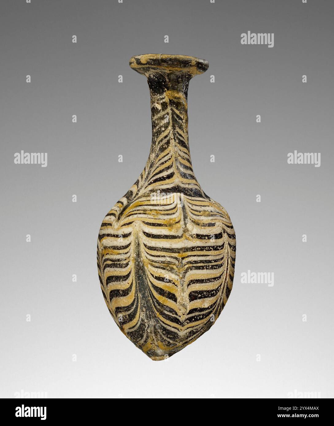 Alabastron, II-i secolo a.C. Fiasca di profumo con motivo piuma. Informazioni aggiuntive: Alabastron di vetro blu scuro (cobalto) con forma a nucleo decorato con sottili fasce di vetro giallo opaco alternato e bianco in un motivo pettinato verticalmente. Anche i fili giallo e bianco decorano il bordo del labbro. Foto Stock