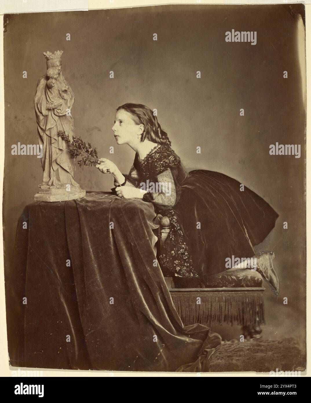 Ritratto di una ragazza, 1858-1881. Una giovane ragazza inginocchiata su una panchina nello studio del fotografo, che guarda una statua della Vergine Maria che tiene in braccio Gesù bambino. Foto Stock