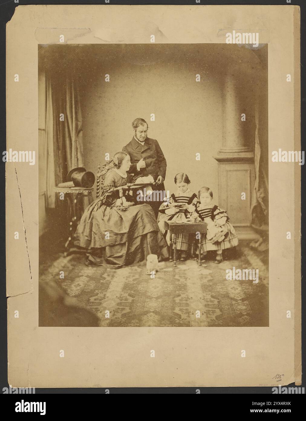 Ritratto di uomo, donna e bambini, circa 1859. Ulteriori informazioni: Ritratto di un uomo, una donna e due bambini. L'uomo è in piedi dietro la donna, che è seduta e ha un vassoio in grembo. Un cappello è su un piccolo tavolo dietro la coppia. I bambini sono in piedi dietro un tavolo in miniatura. Un cane giocattolo è a terra di fronte al gruppo. Foto Stock