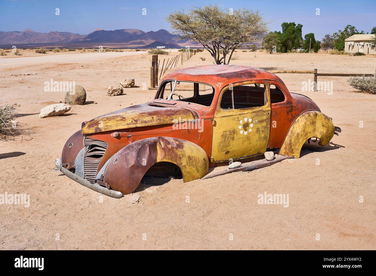 Un vecchio temporizzatore arrugginito, un'auto con orrange e parti di colore giallo, senza finestrini o pneumatici, relitti di auto di Solitare, Namibia Foto Stock