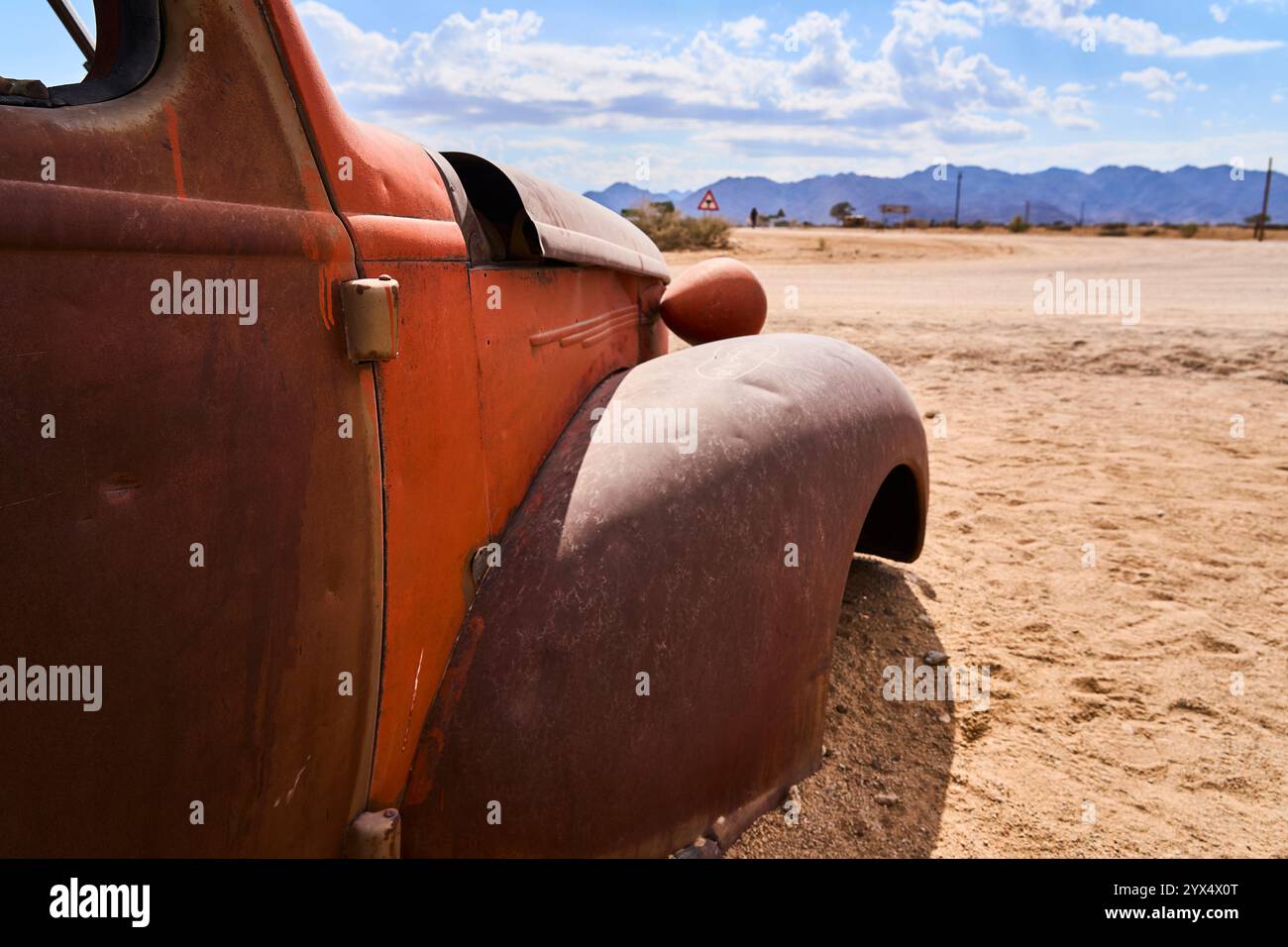 Un vecchio temporizzatore arrugginito, un'auto con orrange e parti di colore giallo, senza finestrini o pneumatici, relitti di auto di Solitare, Namibia Foto Stock