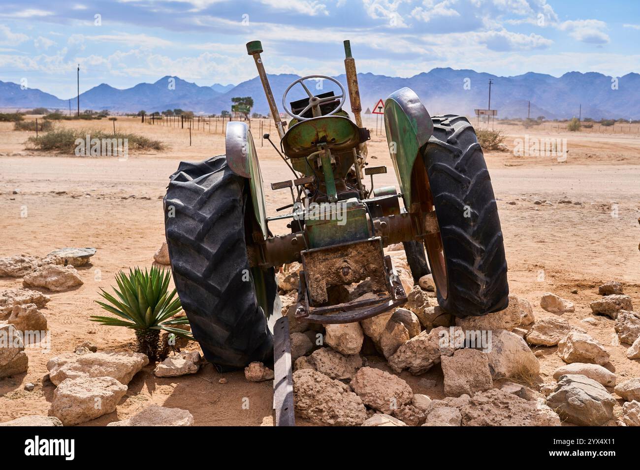 Un vecchio trattore arrugginito con pneumatici sgonfi su un mucchio di rocce, relitti di auto di Solitare, Namibia Foto Stock