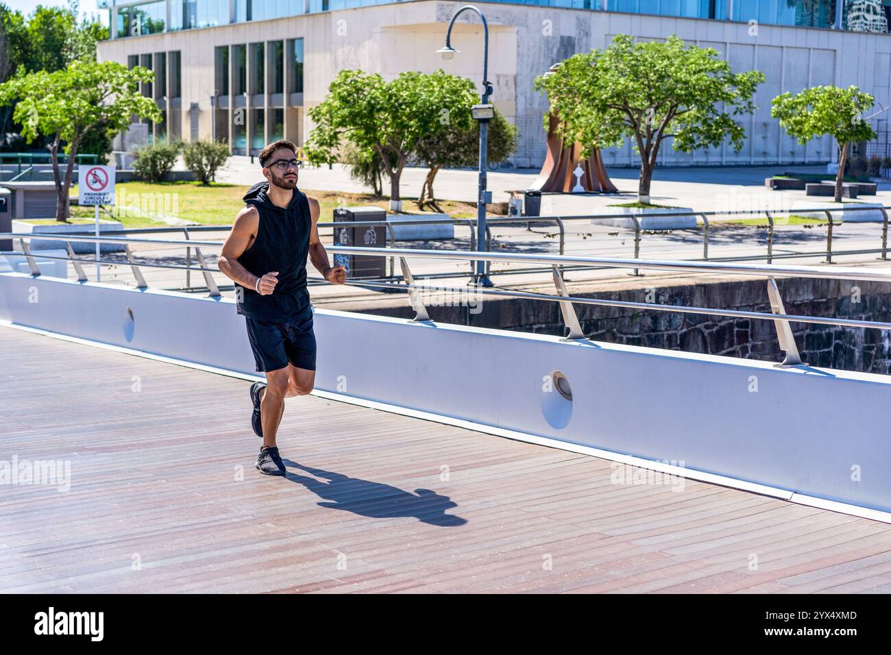 Giovane che fa jogging su un ponte sul canale cittadino. Foto Stock