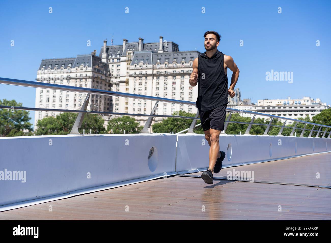 Energico corridore urbano che attraversa un ponte su un canale tranquillo. Foto Stock