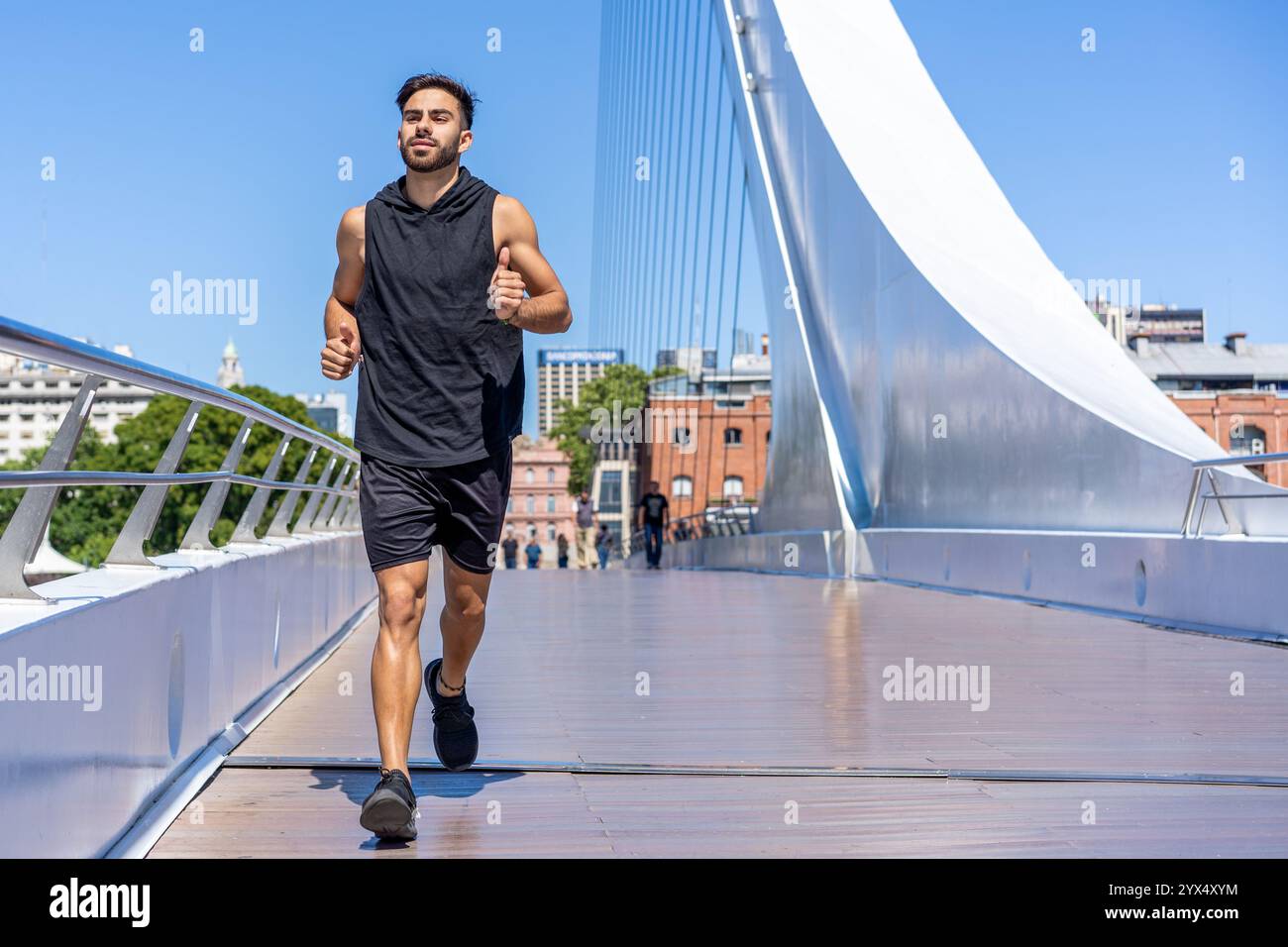 Uomo sportivo che corre su un ponte con vista sul mare in città. Foto Stock