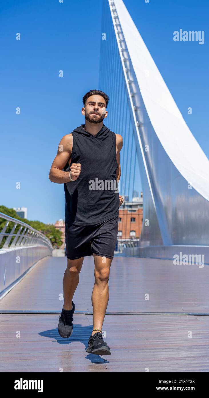 Giovane attivo che corre su un ponte panoramico sopra un canale Foto Stock