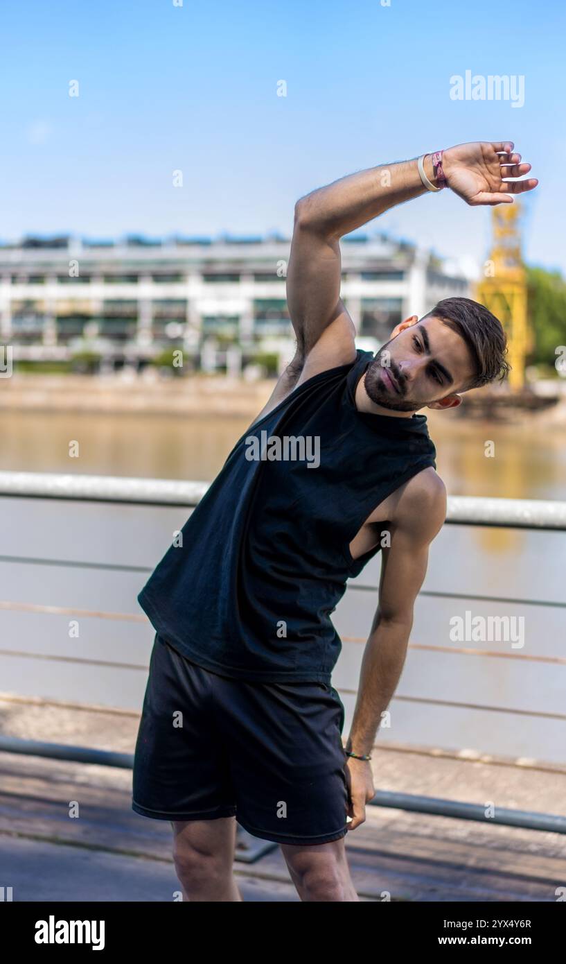 Giovane che esegue un tratto su un sentiero lungo il fiume in città. Foto Stock