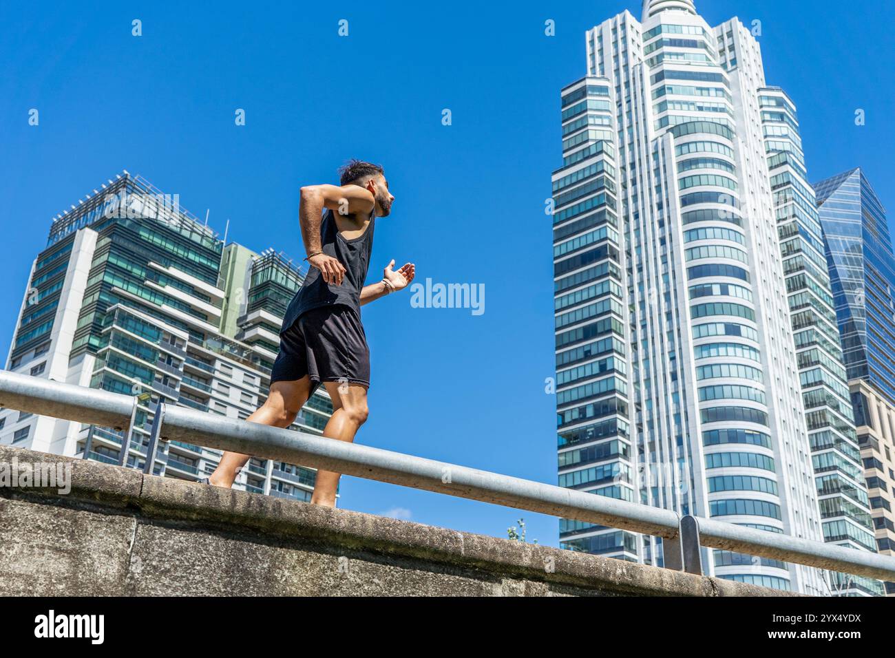 Giovane che si sta impegnando in una corsa rinfrescante lungo un marciapiede della città. Foto Stock