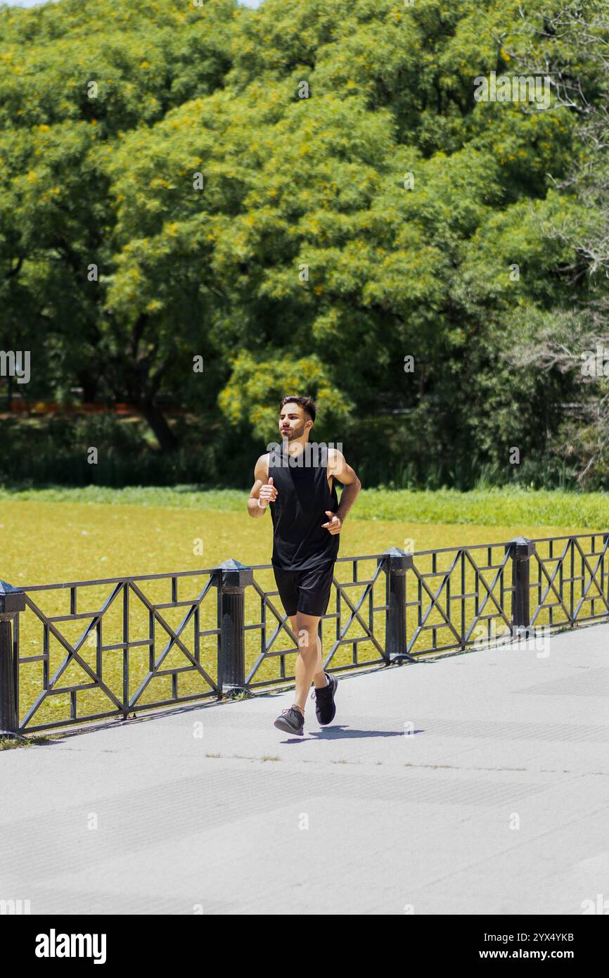 Giovane che fa jogging lungo un lago tranquillo nel parco cittadino. Foto Stock
