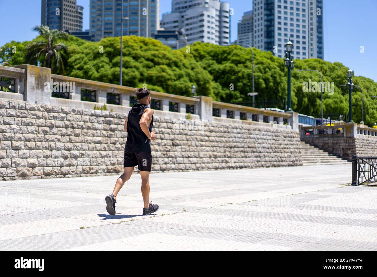 Un giovane energico corre lungo sentieri panoramici in un parco urbano Foto Stock