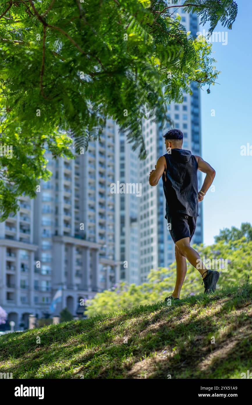 Giovane eccitato che naviga su terreni ondulati in un parco vivace tra eleganti strutture cittadine. Foto Stock