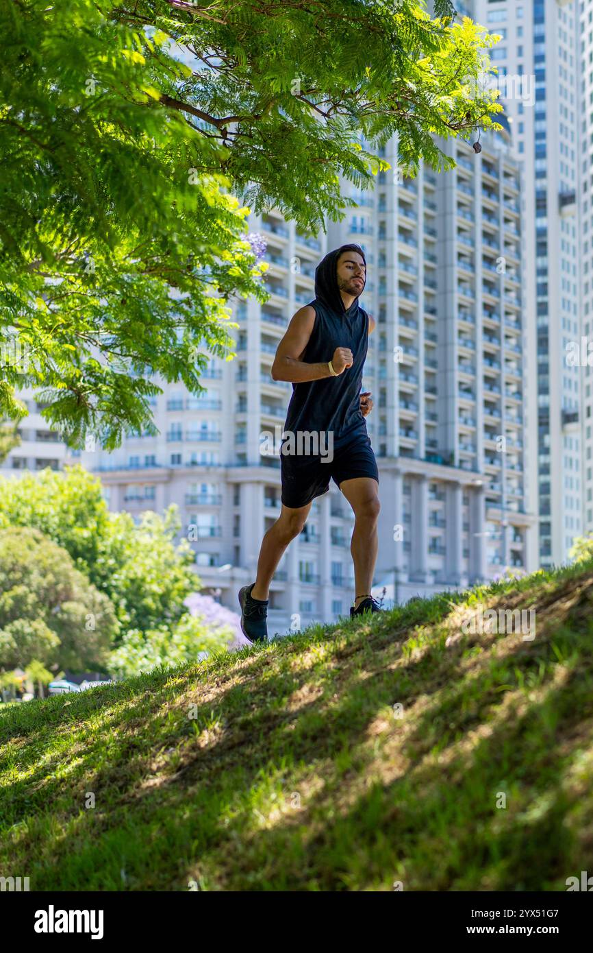 Giovane atleta che conquista piste impegnative in un parco cittadino circondato da edifici torreggianti Foto Stock