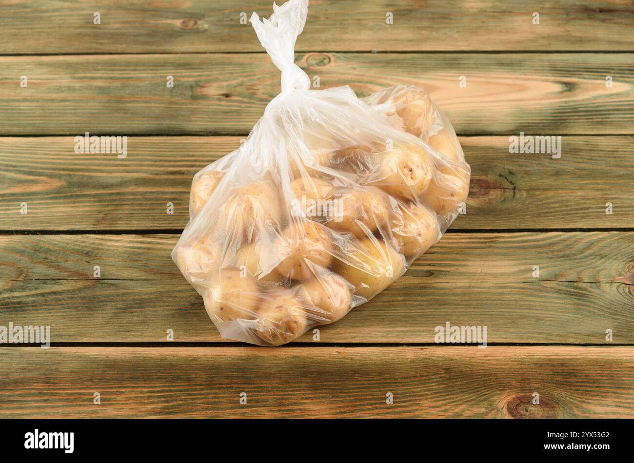Patate novelle in un sacchetto di plastica su una superficie di legno. Copia spazio. Foto Stock