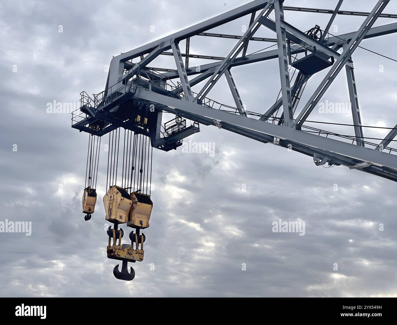 Gru industriale con ganci contro il cielo nuvoloso Foto Stock