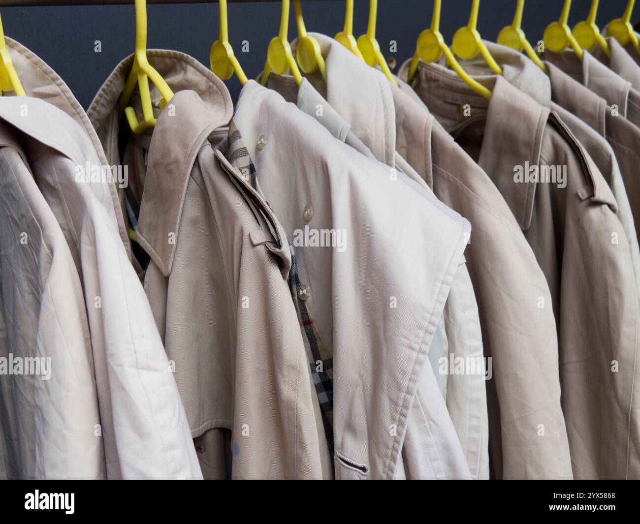 Una barra appendiabiti con impermeabili beige mackintosh Macintosh. Foto Stock