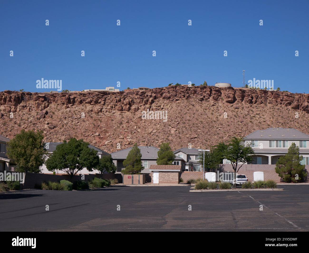 Serbatoio, antenna di comunicazione, case moderne lungo la scarpata che si affaccia sulle case ordinarie e sul parcheggio sottostante. Foto Stock