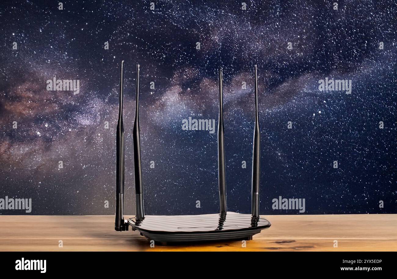 Un router per la distribuzione del Wi-Fi su un tavolo di legno, primo piano, sullo sfondo di un cielo stellato. Foto Stock