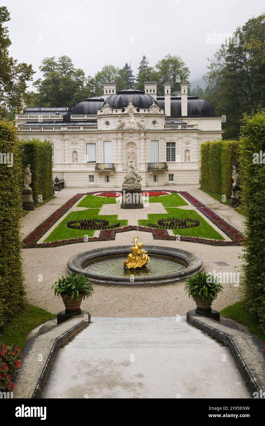 Vista ad alto angolo del parterre con bordi e fontana delimitata da siepi di alberi decidui nel giardino formale del palazzo Linderhof a fine estate. Foto Stock