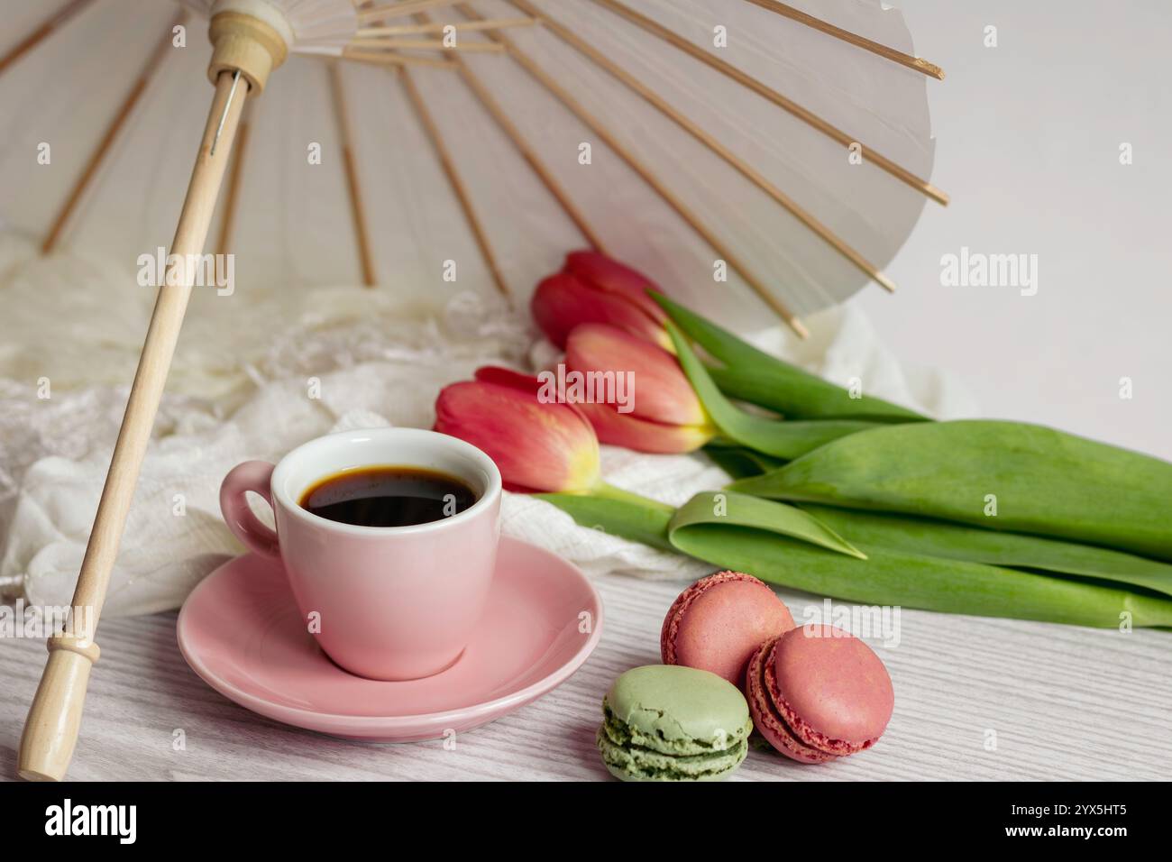 Tazza da caffè rosa con 3 macaron e 3 tulipani Foto Stock