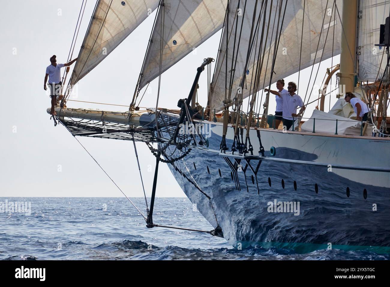 Membri dell'equipaggio su uno yacht a vela d'epoca nelle acque dell'oceano aperto Foto Stock